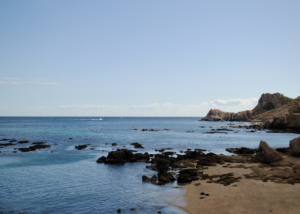 brown rock formation on sea under blue sky during daytime