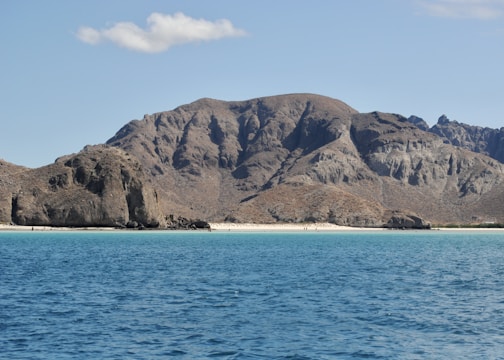 brown and green mountain beside body of water during daytime