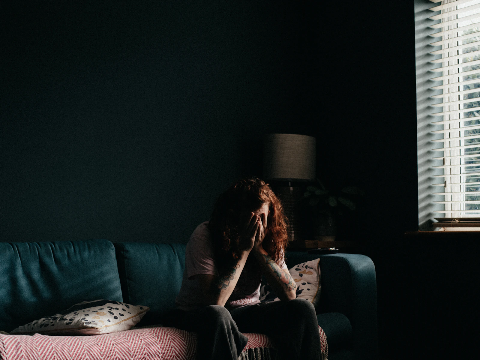 A woman sitting on a couch looking worried and thinking