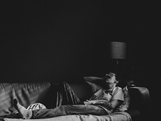 man in black t-shirt lying on couch