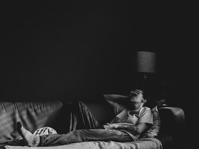 man in black t-shirt lying on couch upset zoom background