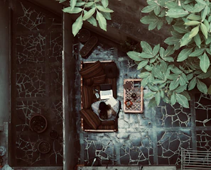 A digital nomad working on a laptop at a sunny outdoor café with tropical plants around.