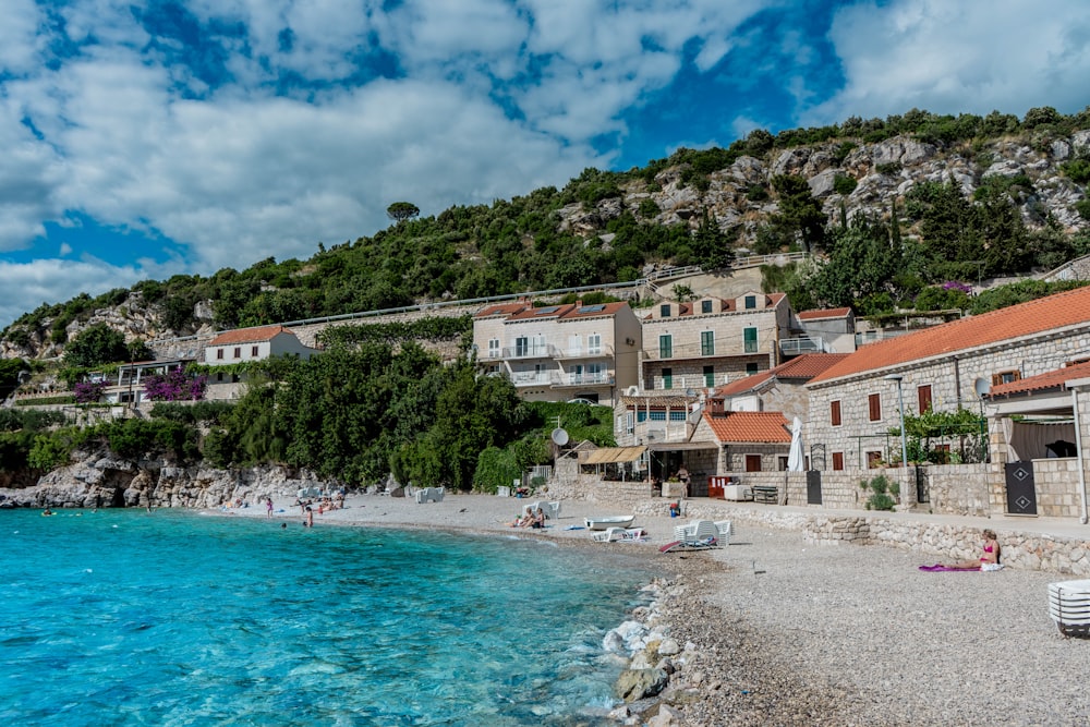 people on beach near houses under blue sky during daytime