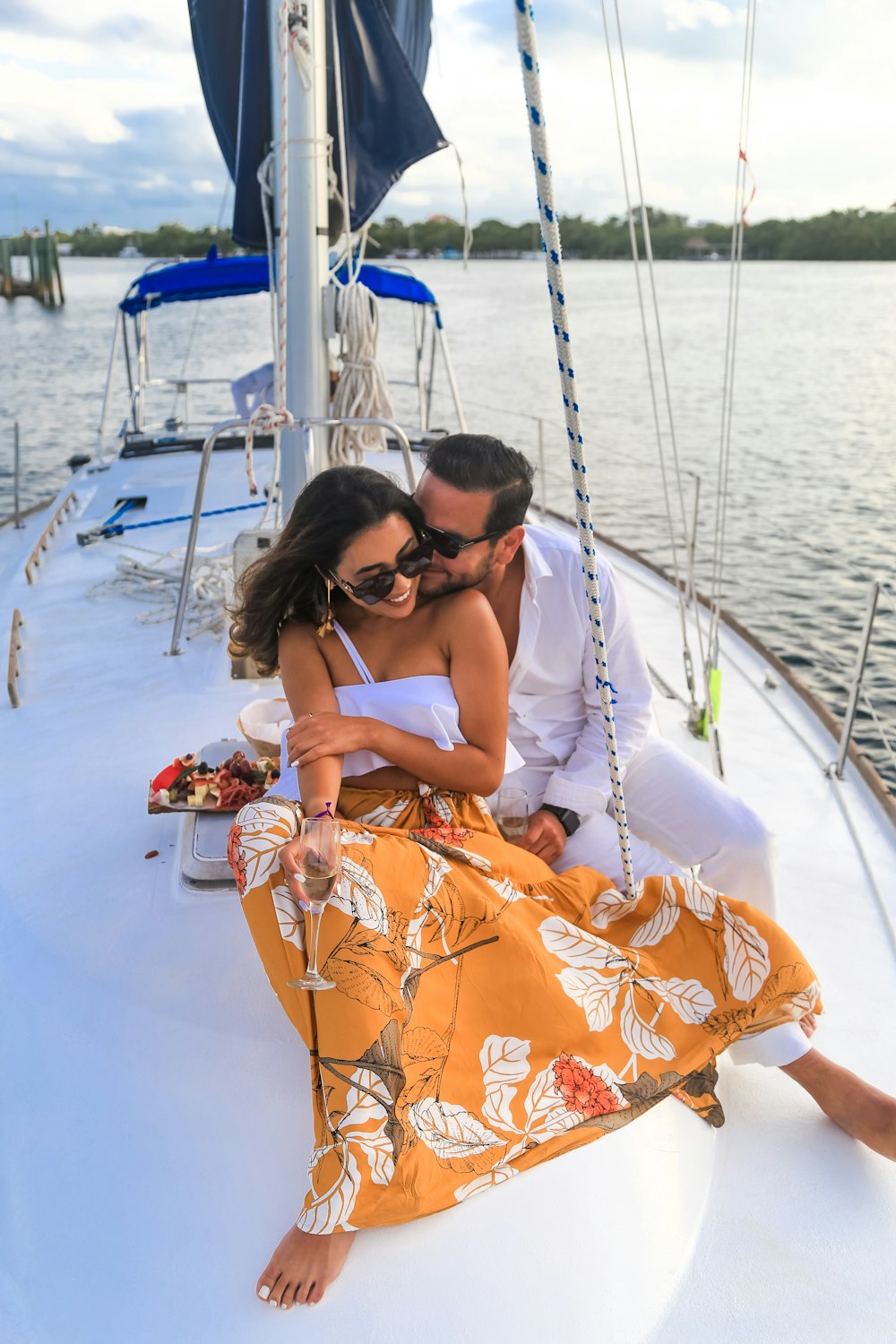 woman in orange and white floral tube dress wearing black sunglasses sitting on white boat during