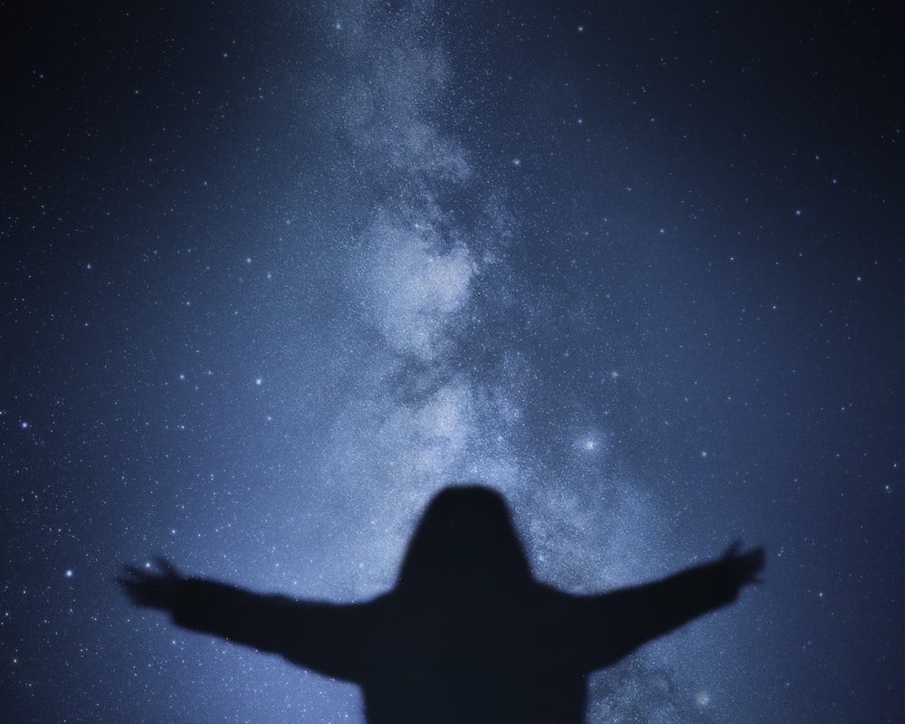 silhouette of persons hand under blue sky