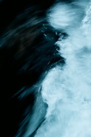 A dynamic, abstract representation of flowing water with a mixture of dark and light swirls. The motion creates a sense of movement and texture.