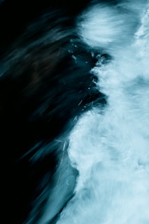 A dynamic, abstract representation of flowing water with a mixture of dark and light swirls. The motion creates a sense of movement and texture.