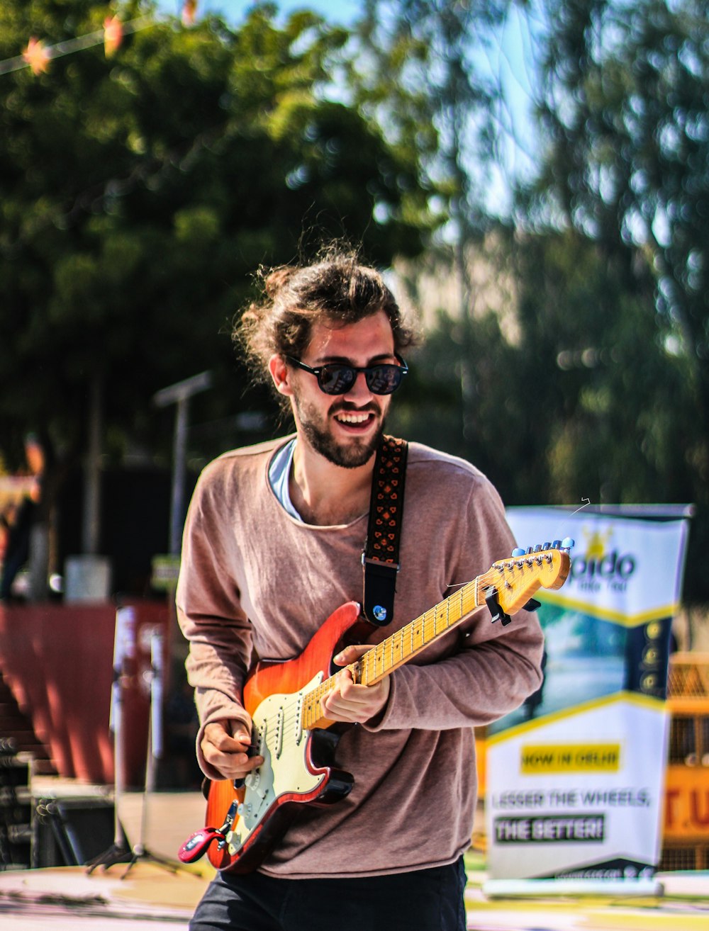 man in gray crew neck long sleeve shirt playing orange electric guitar