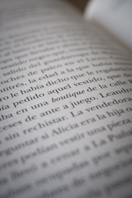 A close-up view of text on a book page, showing several lines of Spanish writing in black ink on white paper. The camera focus creates a soft blur effect on parts of the text.
