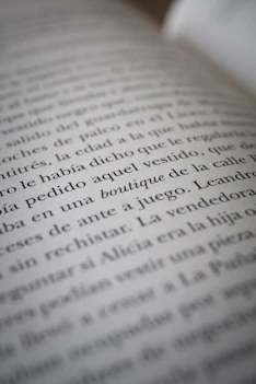 A close-up view of text on a book page, showing several lines of Spanish writing in black ink on white paper. The camera focus creates a soft blur effect on parts of the text.