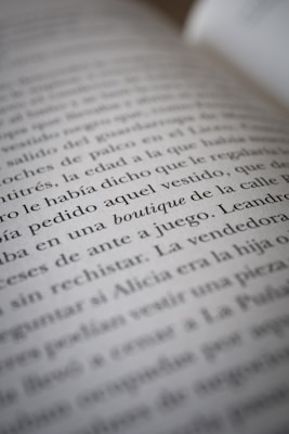 A close-up view of text on a book page, showing several lines of Spanish writing in black ink on white paper. The camera focus creates a soft blur effect on parts of the text.