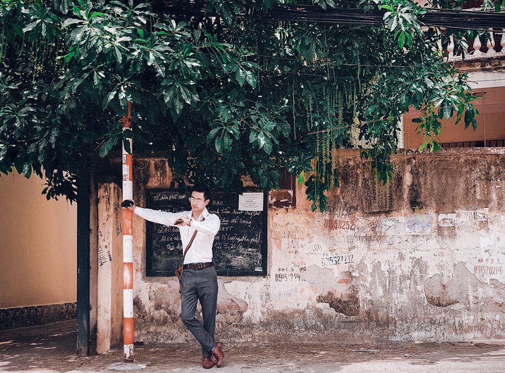 man in black vest and blue denim jeans standing near green leaf tree during daytime