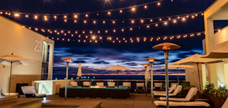 An elegant outdoor patio glowing under string lights and lanterns during twilight.