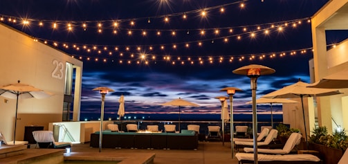 A cozy outdoor patio softly lit by colorful smart lights glowing against a twilight sky.