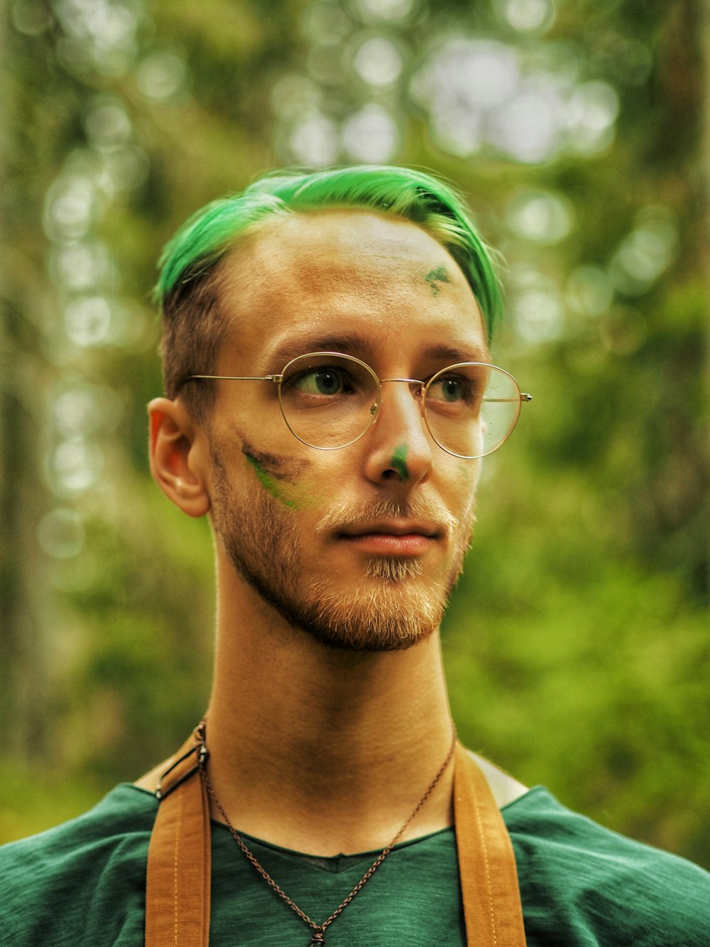 man in white collared shirt with green and yellow powder on his face