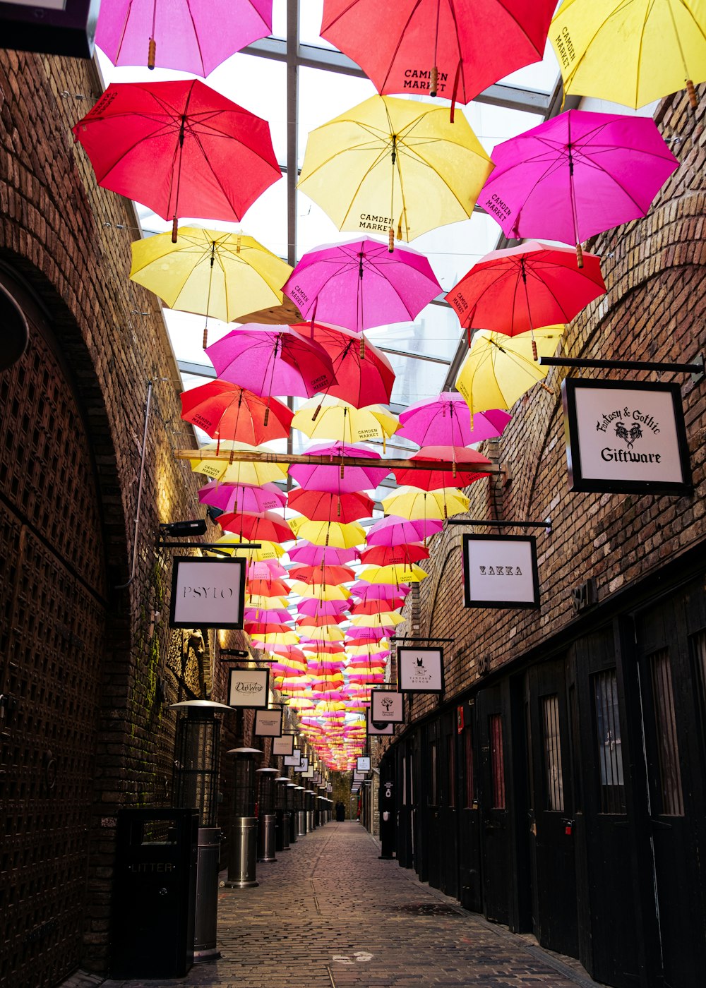 Verschiedene Regenschirme, die an einer braunen Ziegelmauer hängen