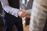 A professional handshake between two business people in formal attire.