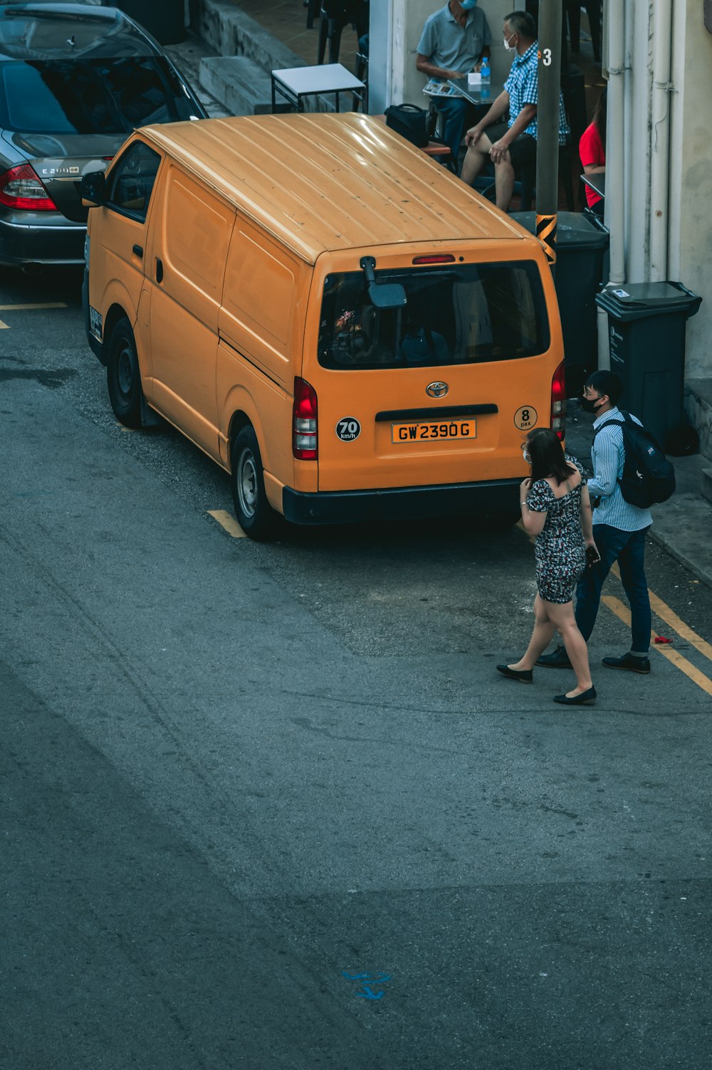 woman in black and white floral dress standing beside yellow van