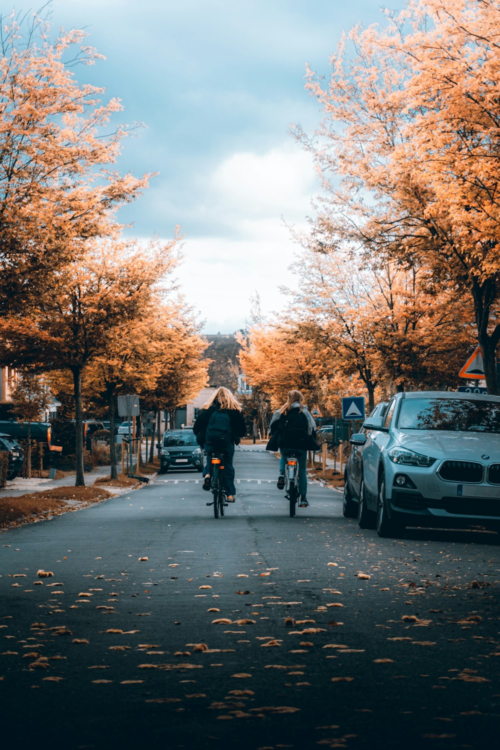 people walking on sidewalk near cars parked on sidewalk during daytime