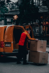 man in red jacket standing beside orange van during daytime