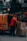 man in red jacket standing beside orange van during daytime