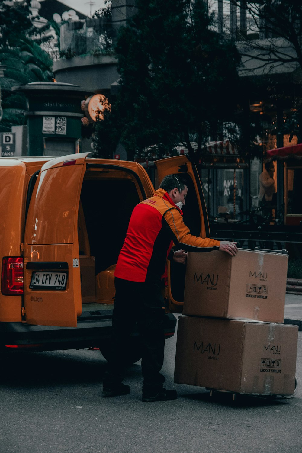 Mann in roter Jacke tagsüber neben orangefarbenem Van