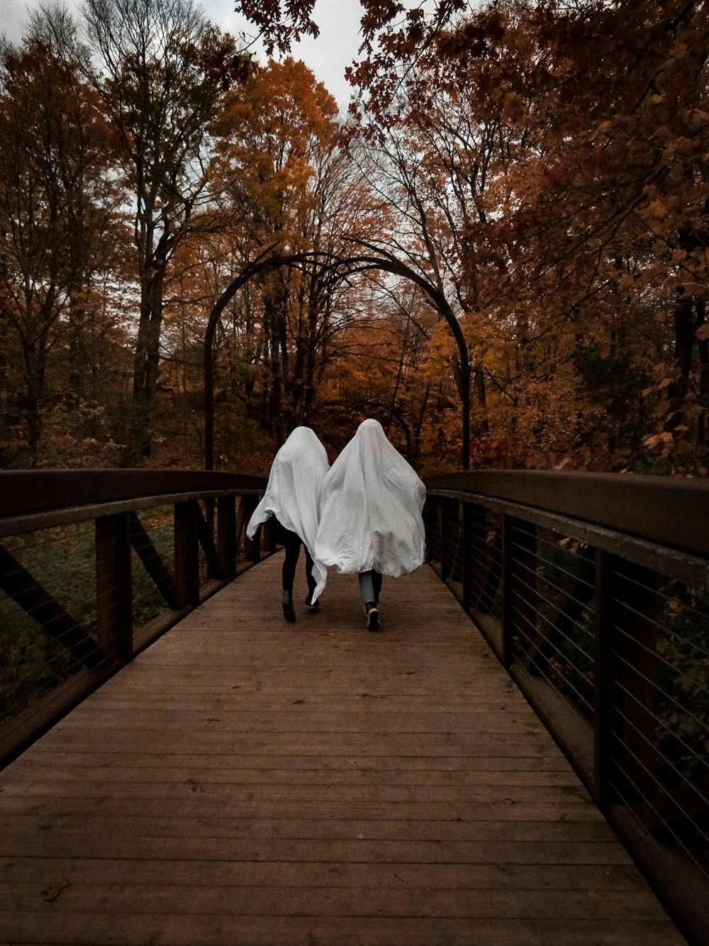 woman in white dress walking on wooden bridge
