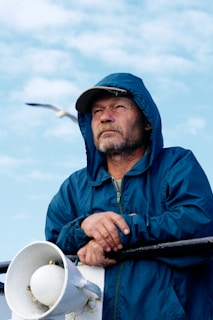 man in blue zip up hoodie holding black and white stick