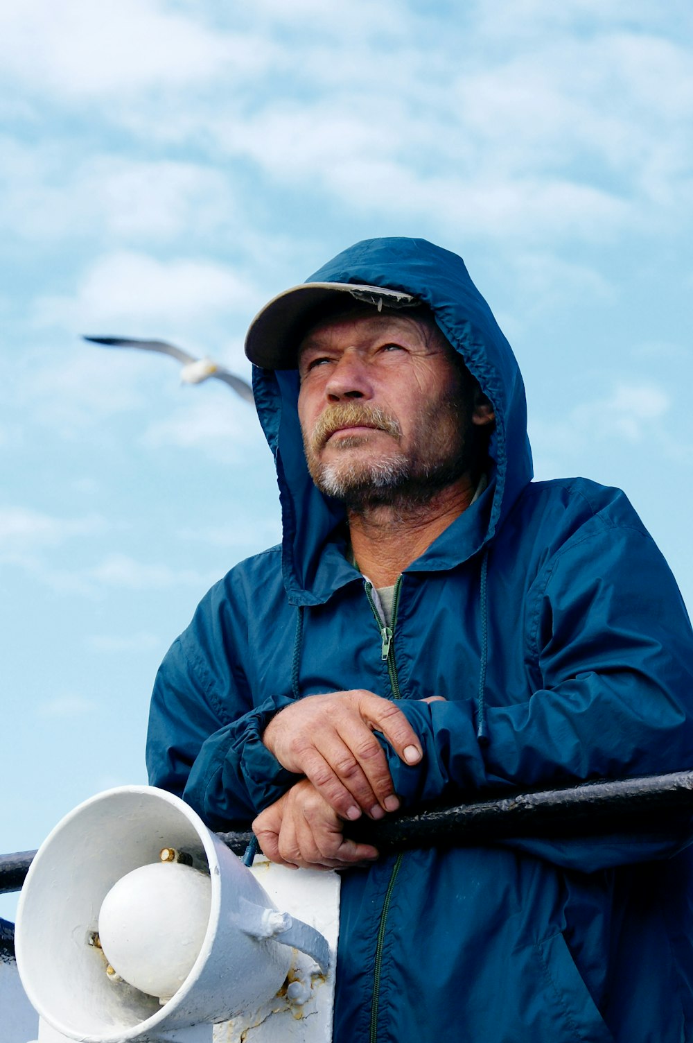 hombre en sudadera con cremallera azul con capucha sosteniendo palo blanco y negro