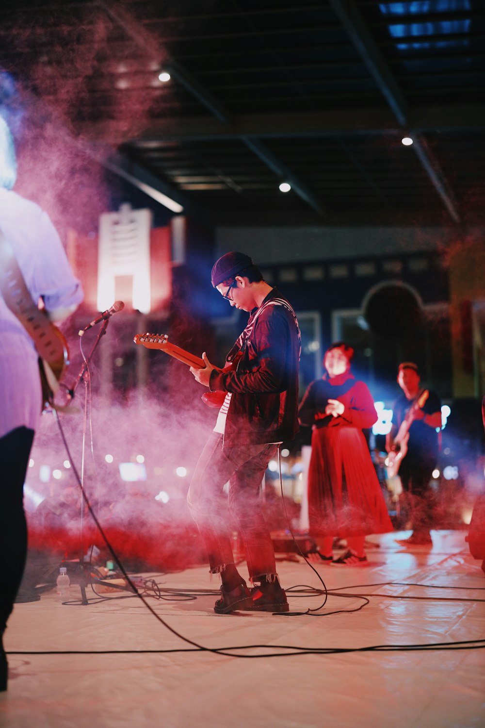 man in white shirt playing electric guitar on stage