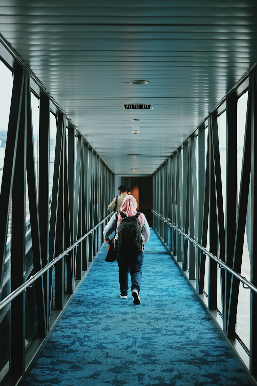 man in black jacket and black pants walking on hallway