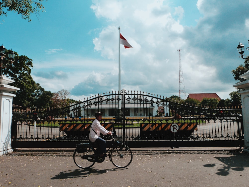 man in white shirt riding bicycle on road during daytime