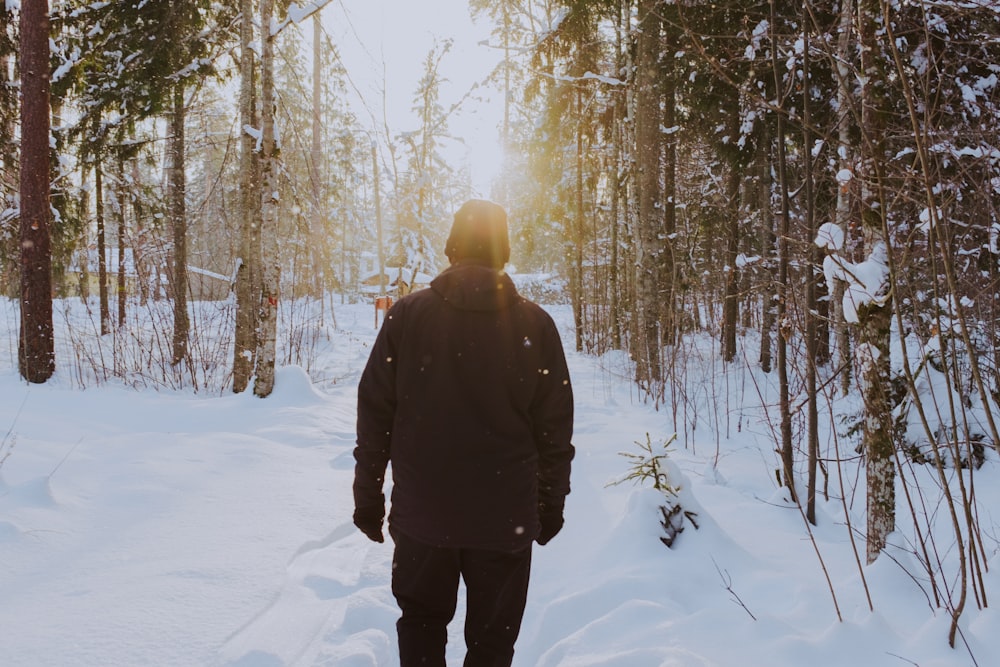 person in black jacket standing on snow covered ground during daytime