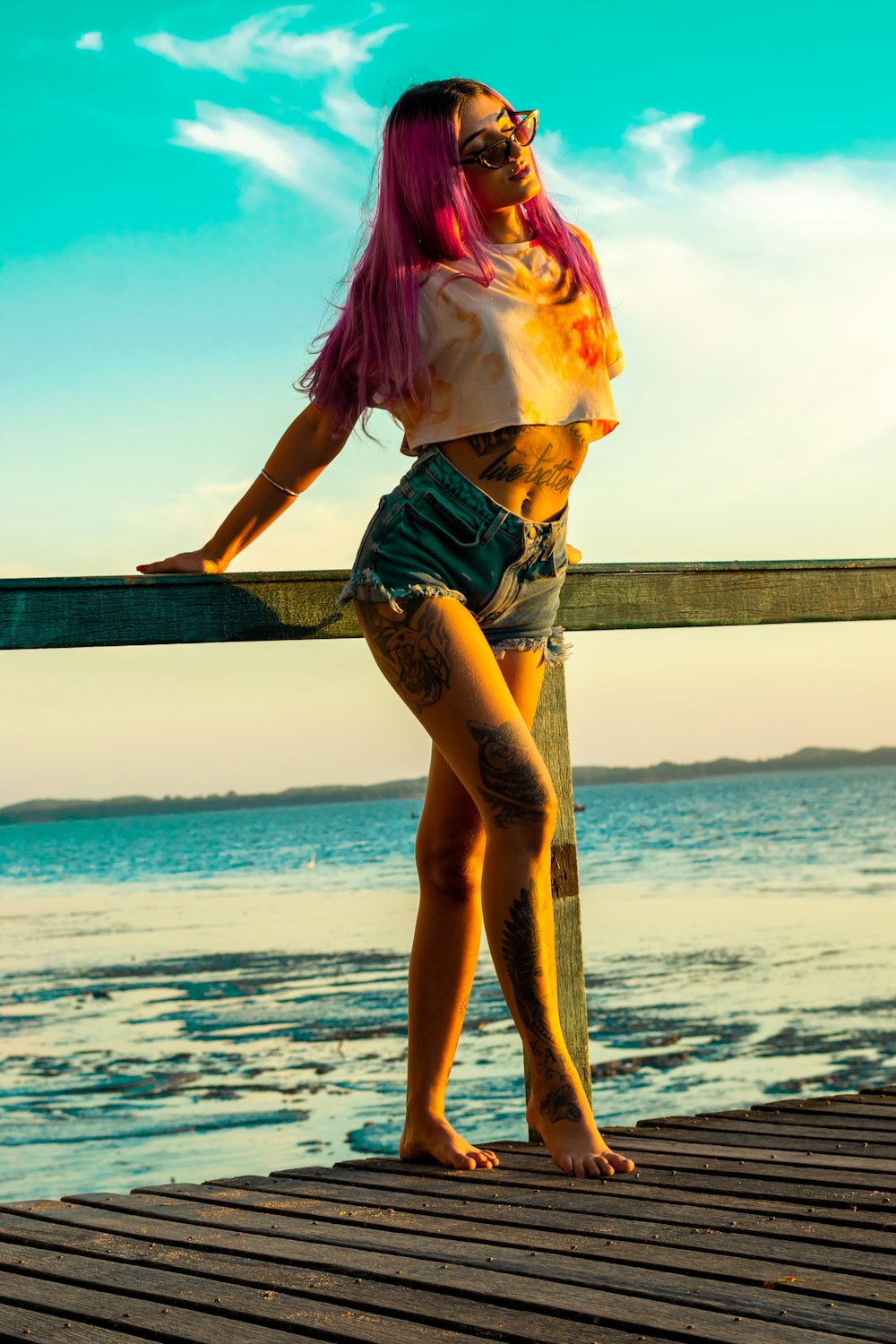 woman in pink and yellow bikini standing on wooden dock during daytime
