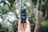 A happy customer holding a snapgo360 camera outdoors with a scenic background.