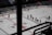 A group of ice hockey players wearing red uniforms is seen on the rink spread out in formation, likely part of a team lineup or practice session. The arena appears to be relatively empty, with a few spectators visible in the stands. Advertisements in Russian line the surrounding boards of the rink.