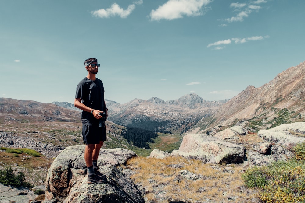 man in black crew neck t-shirt standing on rocky hill during daytime