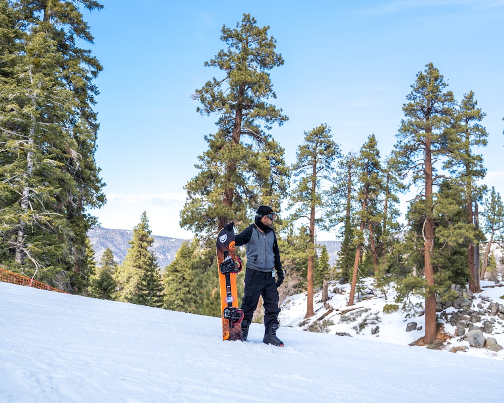 man in black jacket and orange pants standing on snow covered ground during daytime