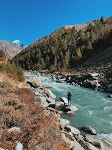 river in between green and brown mountains under blue sky during daytime