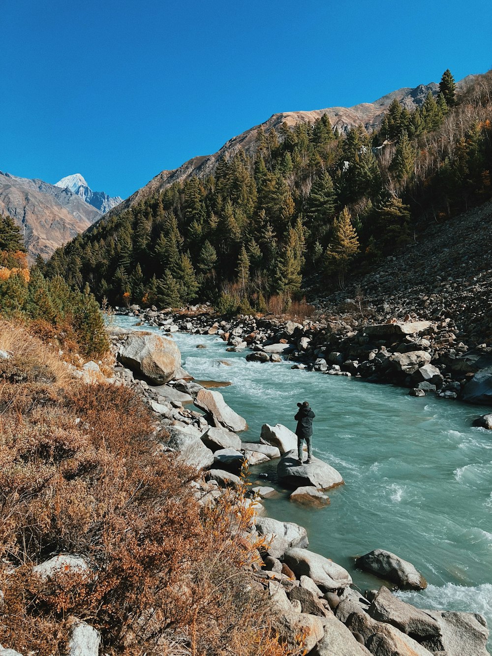 river in between green and brown mountains under blue sky during daytime