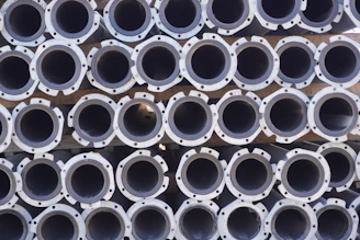 Close-up of royal blue and white PVC pipes neatly stacked in a bright, clean manufacturing facility.