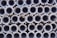 A large stack of metal pipes arranged in neatly aligned rows and columns.