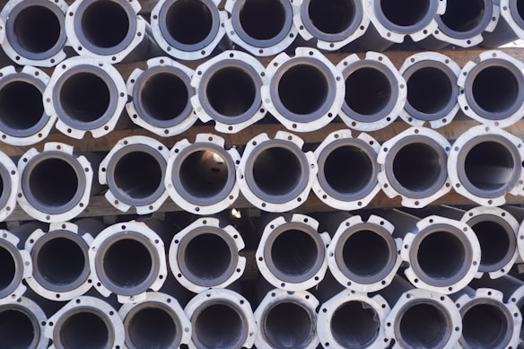 A large stack of metal pipes arranged in neatly aligned rows and columns.
