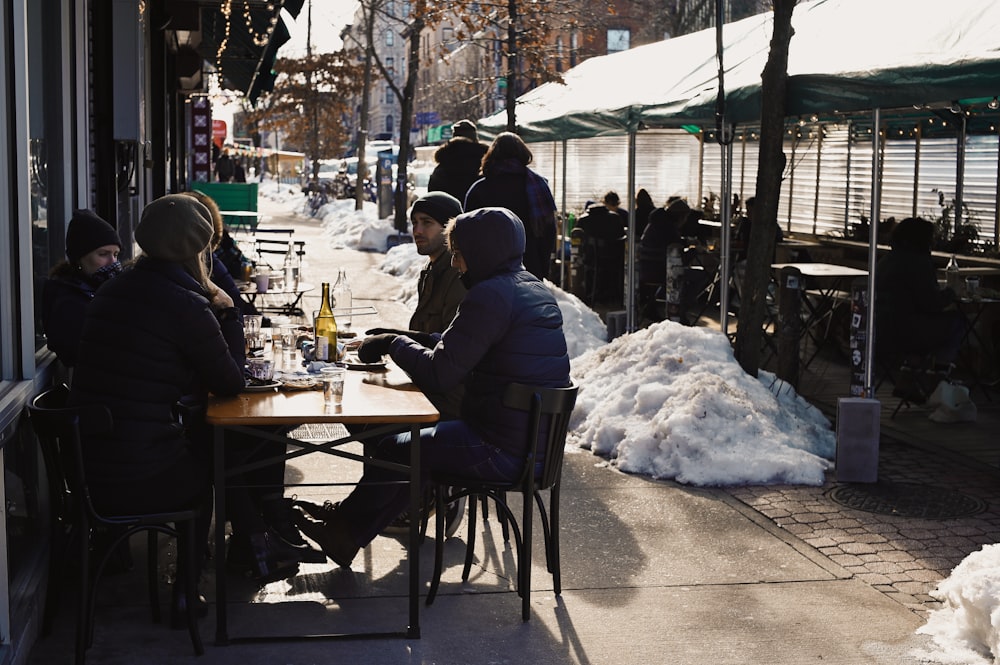 people sitting on chair in front of table covered with snow during daytime