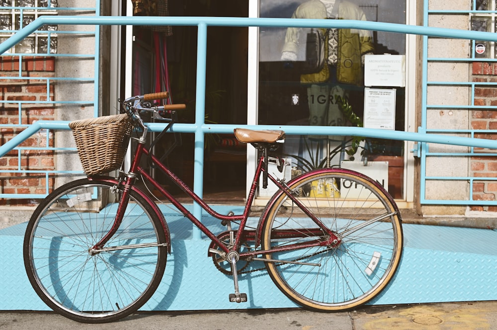 red city bike parked beside blue wooden framed glass window