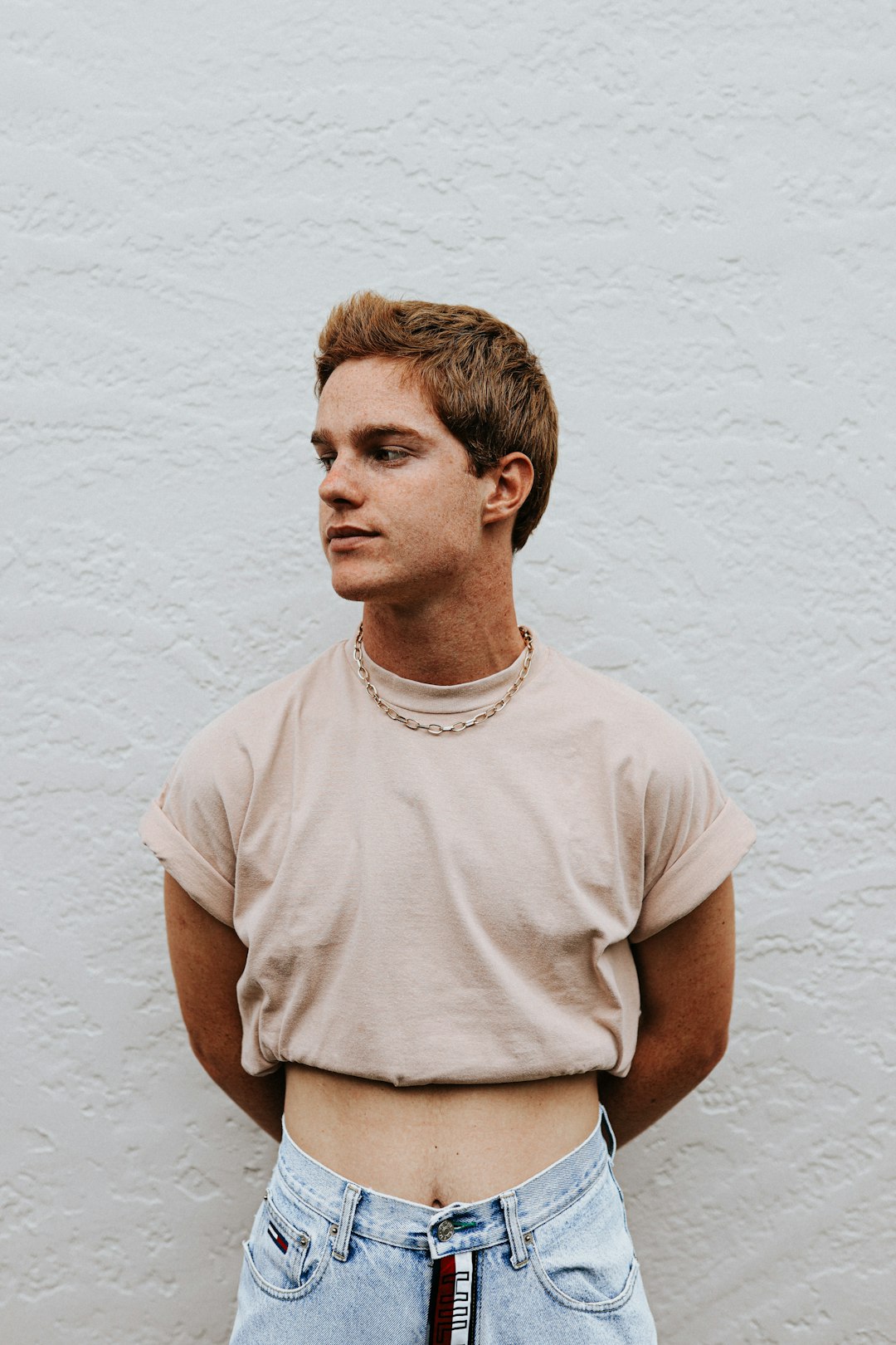 man in white crew neck t-shirt standing beside white wall