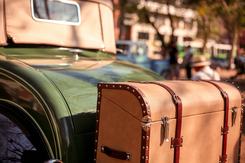 green car with brown leather suitcase