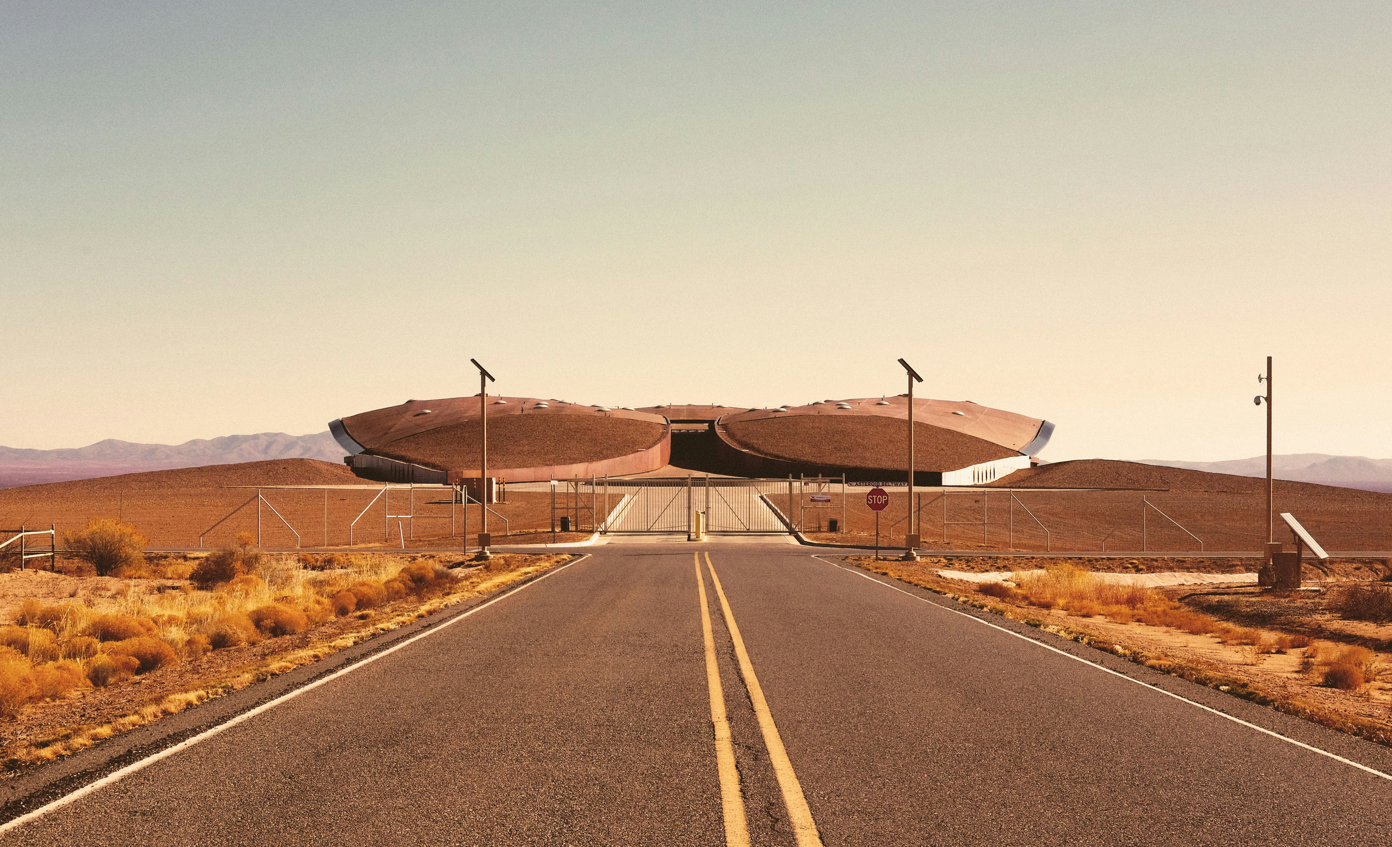 gray asphalt road between brown field under gray sky during daytime