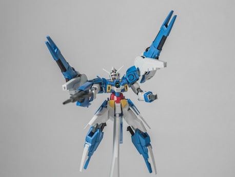 A detailed model of a robot with an intricate design, highlighted by a combination of blue, white, and red colors, equipped with large wings and holding a weapon.