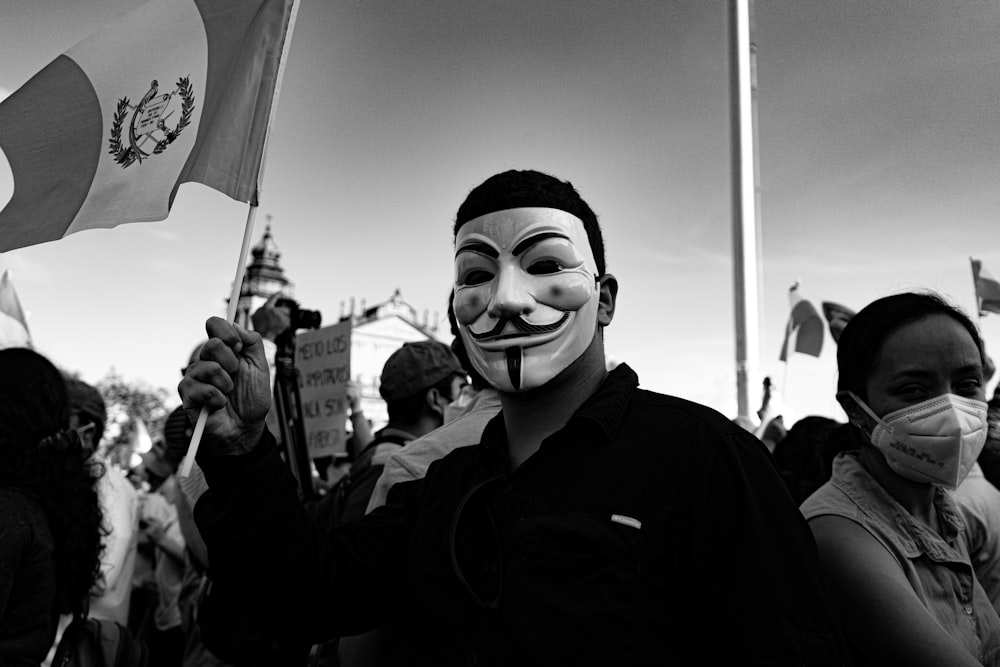 grayscale photo of man wearing mask and holding umbrella